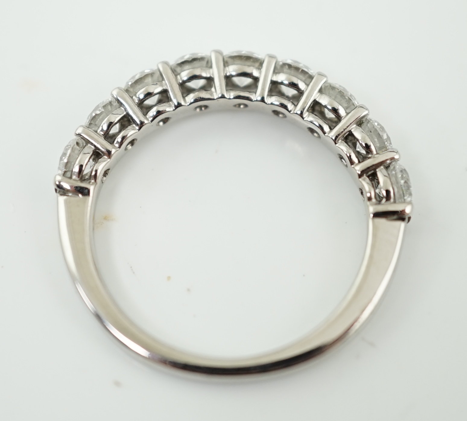 A white gold and nine stone set round brilliant cut diamond set half hoop ring